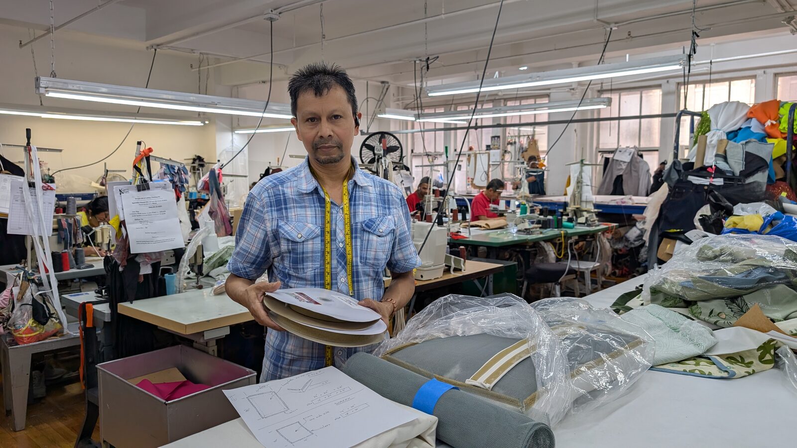 The workshop floor in Manhattan's garment district, with a roll of metal screen and the pattern drawing on the cutting table