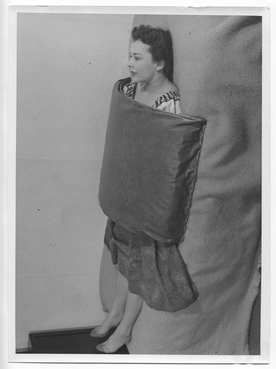 Archival photograph of a woman lying beneath Reich's original arched orgone blanket